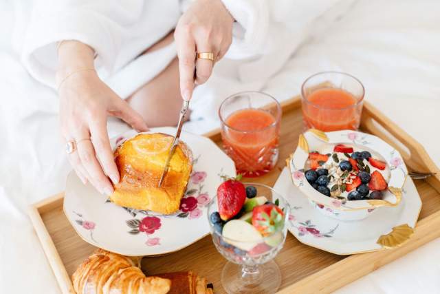 Petit-déjeuner servi au lit avec jus d'orange, fruits et mets gourmands à la Villa Roubia