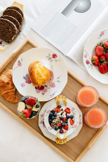 Plateau de petit-déjeuner complet avec croissant, fruits frais et jus à la Villa Roubia