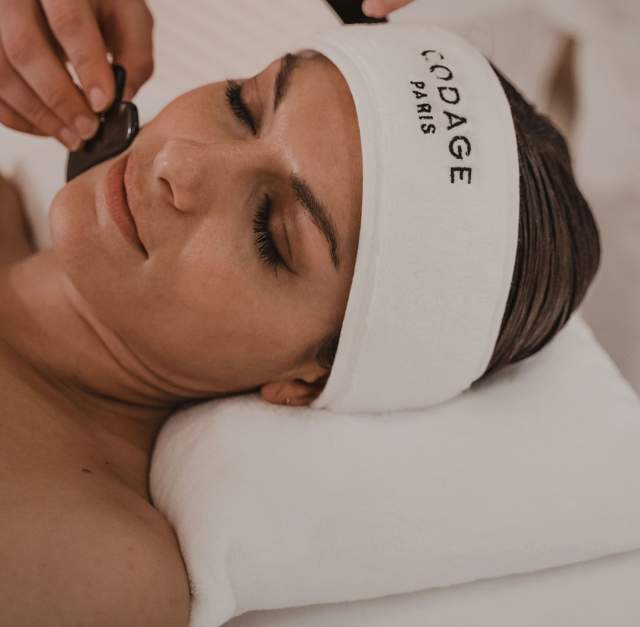 Soin visage avec bandeau et produits cosmétiques de luxe au spa de la Villa Roubia