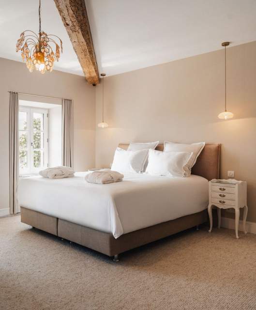 Suite Elegance avec poutres en bois apparentes et lustre fleuri doré - Galerie Villa Roubia