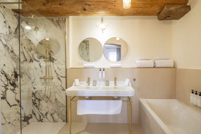 Salle de bain lumineuse dans une suite élégance à Villa Roubia. Poutre apparente, baignoire et douche à l'italienne. 