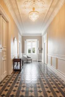 Couloir de la Villa Roubia avec carrelage ancien à motifs et grand chandelier. 